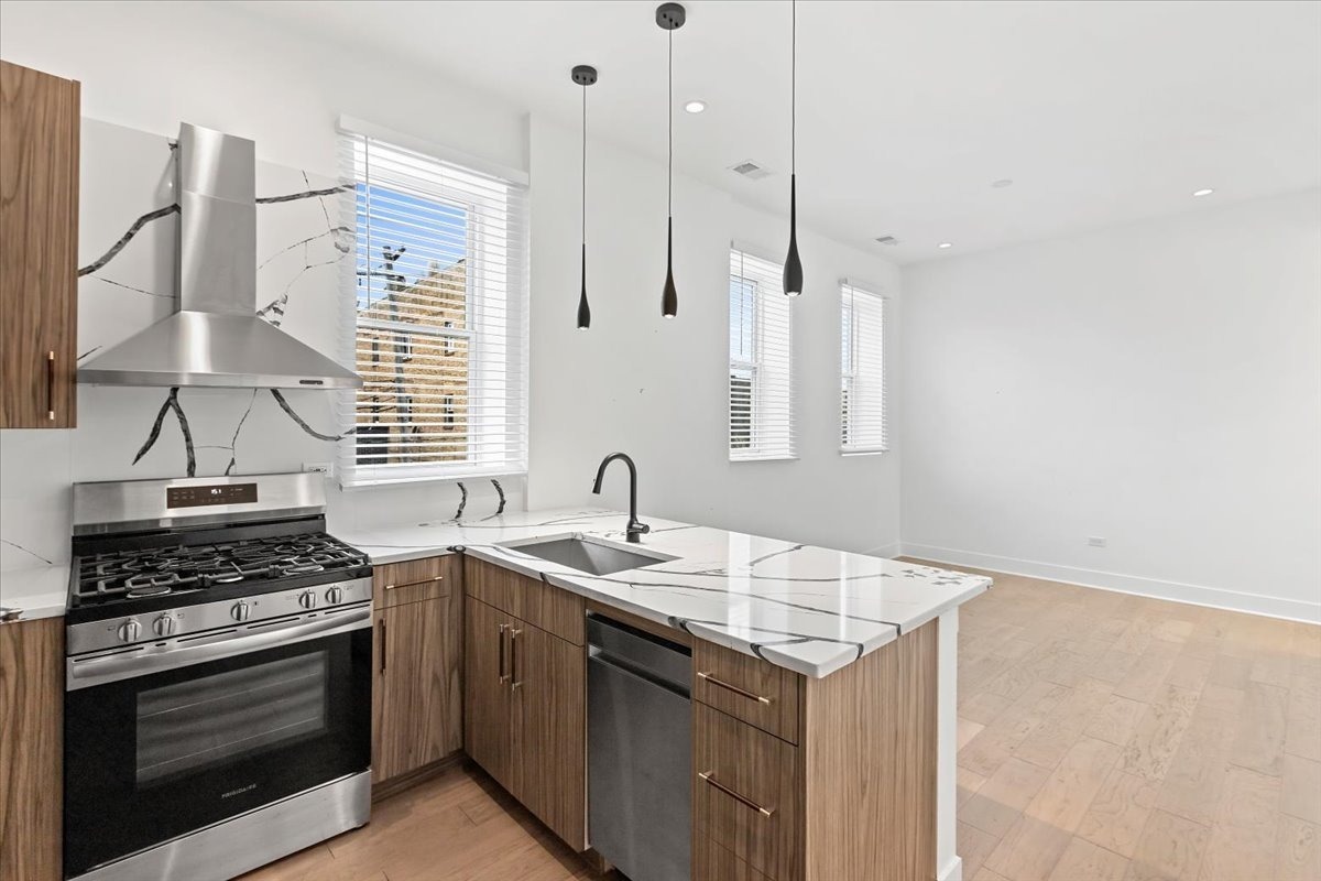 449 North Elizabeth Street, Unit 3S Chicago, IL 60642 - Photo 6 of 12 a kitchen with stainless steel appliances a stove a sink a counter space and a window