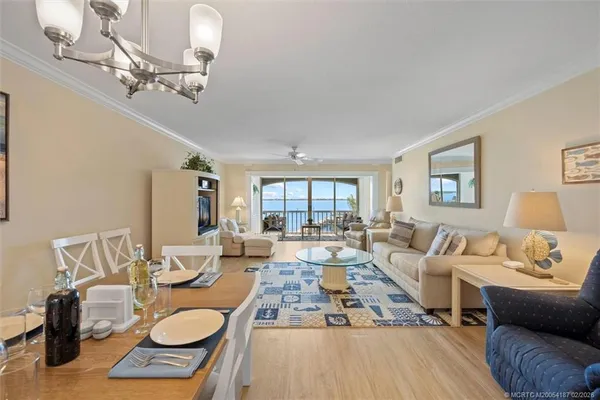 a dining room with wooden floor a chandelier a wooden table and chairs