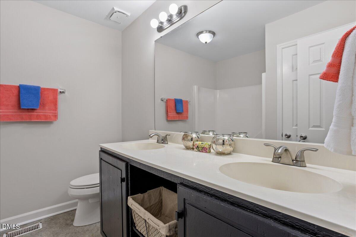 805 Rand Road Garner, NC 27529 - Photo 36 of 38 a bathroom with a granite countertop sink a toilet and a mirror