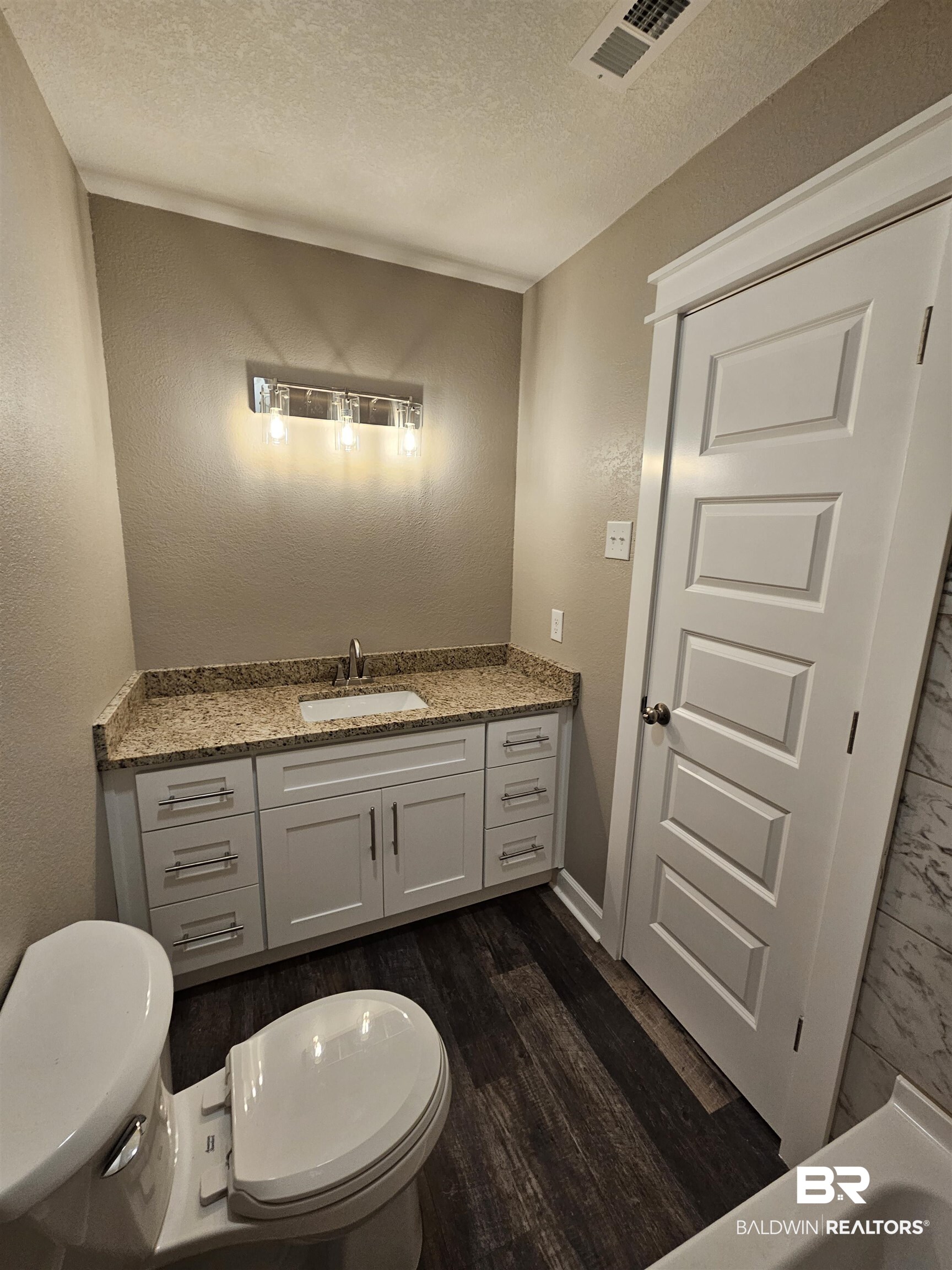 138 Wicker Way Daphne, AL 36526 - Photo 13 of 32 Bathroom featuring a textured wall, a textured ceiling, vanity, and dark wood-style floors