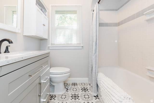 227 West 200 North Logan, UT 84321 - Photo 23 of 44 Bathroom featuring a patterned tile floor, a grey vanity with a white countertop and matte black faucet, a white toilet, and a bathtub with white subway tile surround and a grey accent band