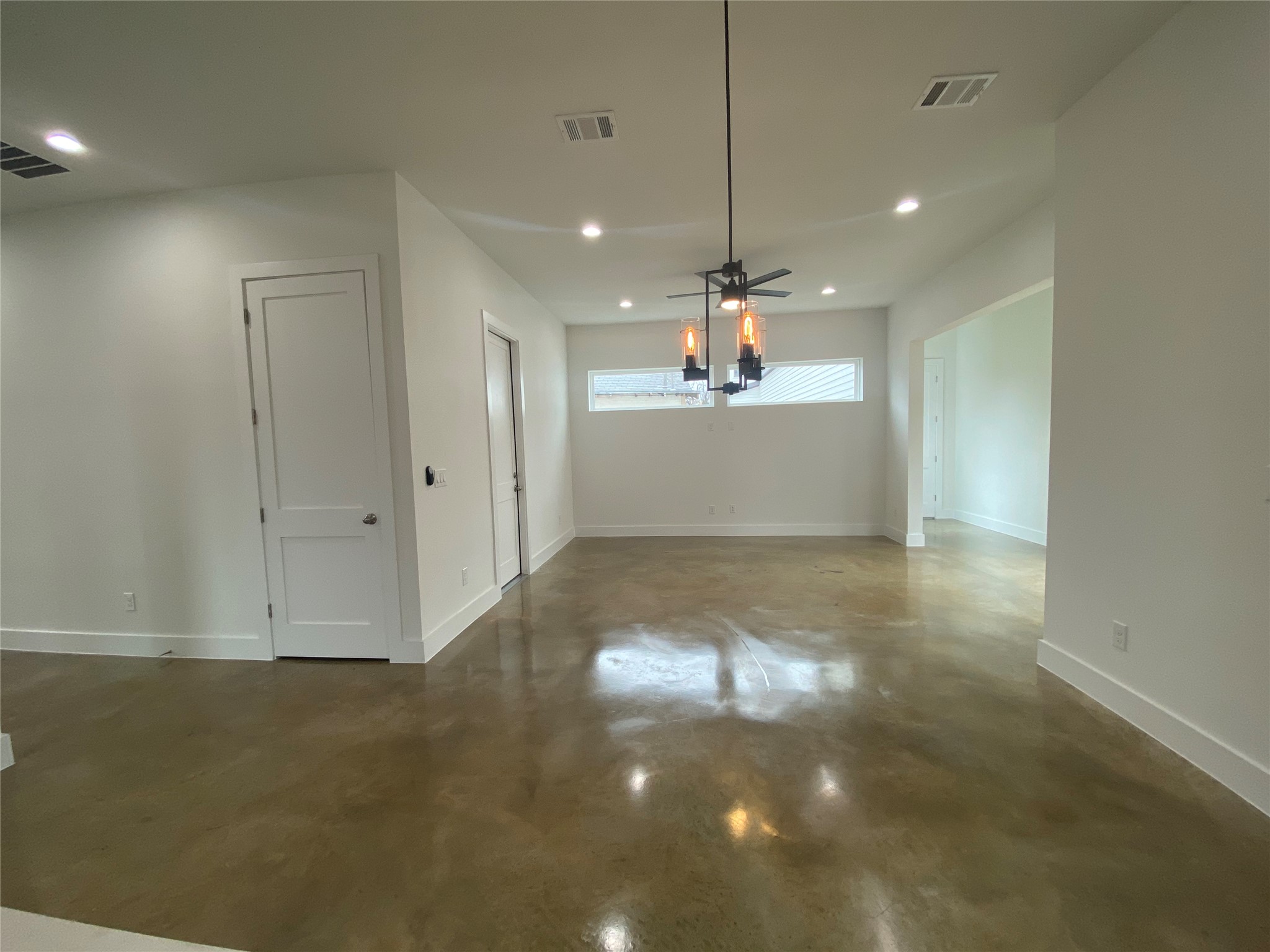 1916 Webberville Road, Unit B Austin, TX 78721 - Photo 9 of 25 Open concept area featuring polished concrete flooring, recessed lighting, white walls, and a modern chandelier with exposed Edison bulbs