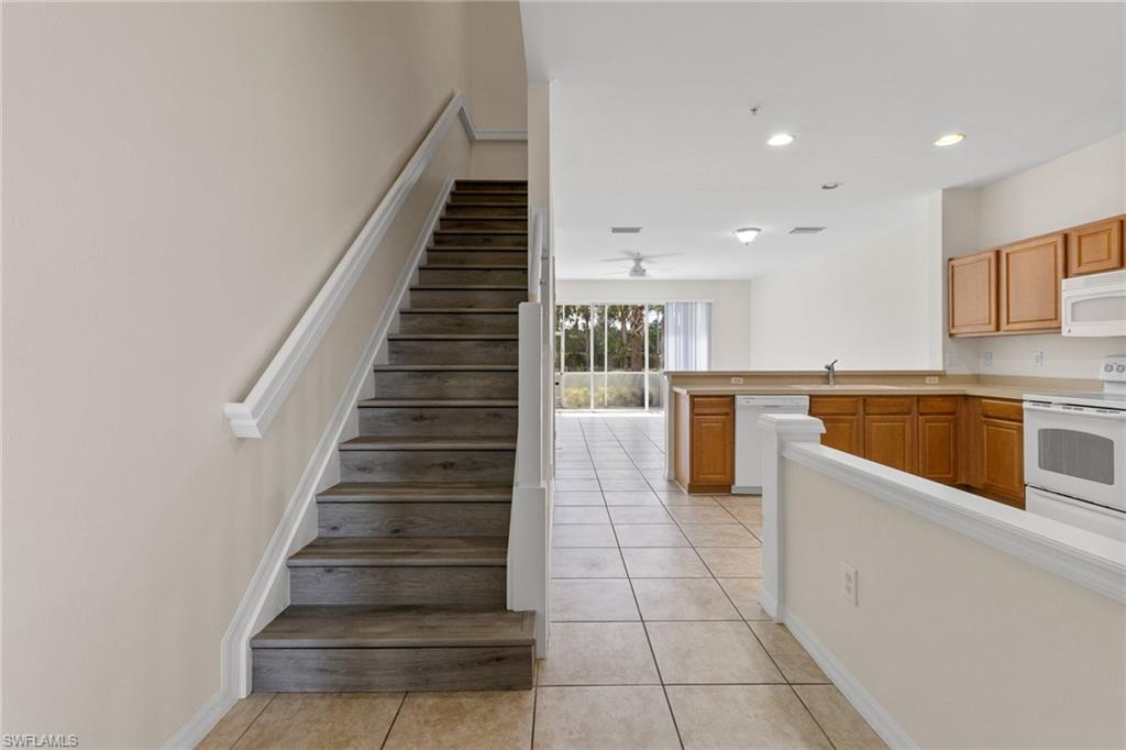 16235 Ravina Way Naples, FL 34110 - Photo 3 of 18 Wood-finish stairs with white risers, tiled flooring, wood cabinetry, built-in kitchen appliances, and a ceiling fan