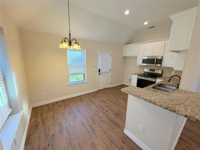 a kitchen with granite countertop a sink cabinets and wooden floor