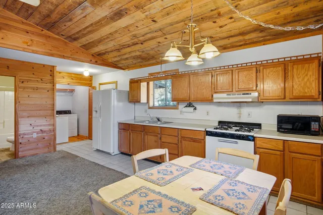 a kitchen with stainless steel appliances granite countertop a sink a stove a refrigerator cabinets and a dining table with wooden floor