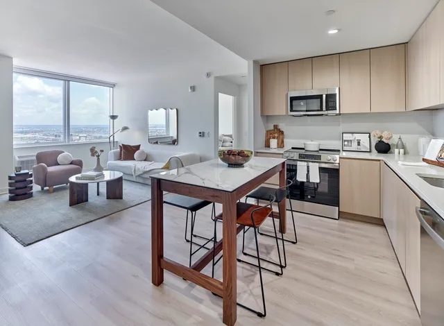 a kitchen with stainless steel appliances granite countertop a stove a refrigerator a sink a dining table and chairs with wooden floor