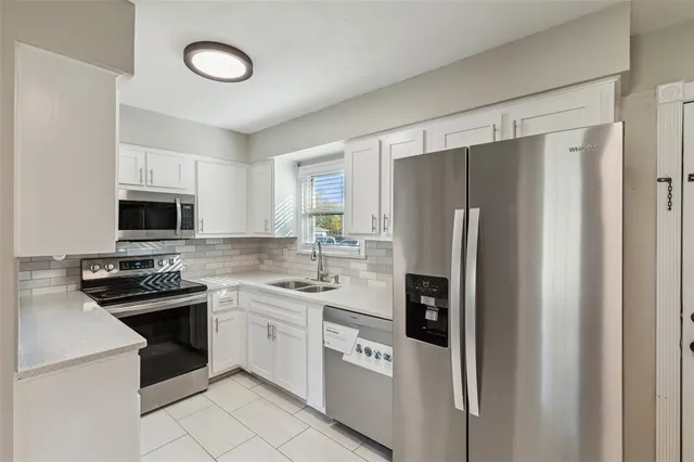 a kitchen with stainless steel appliances a refrigerator sink and white cabinets