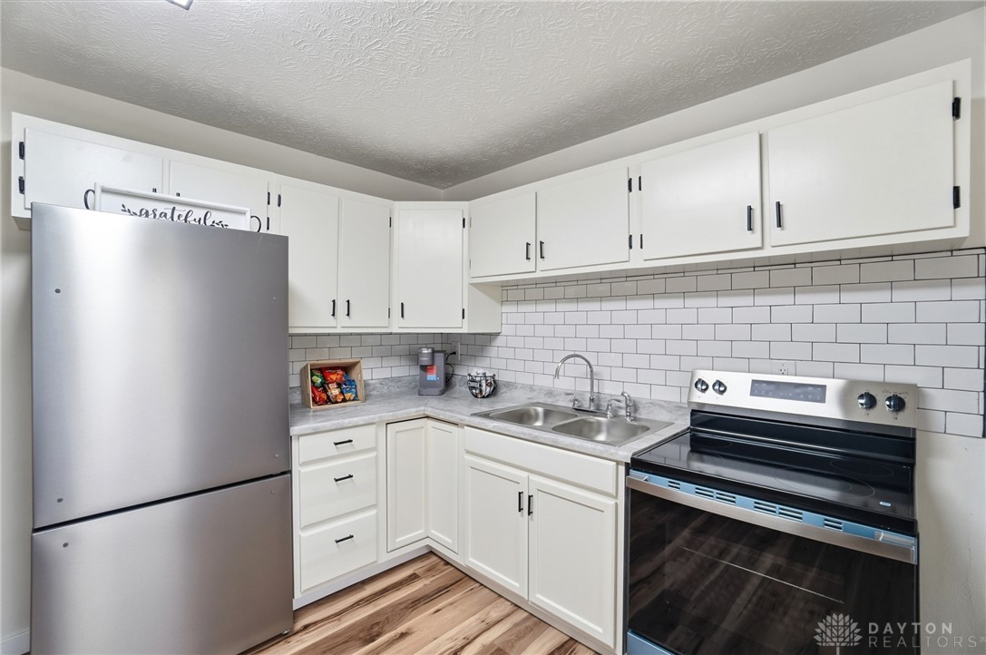 1923 Portage Path Springfield, OH 45506 - Photo 15 of 40 A well-appointed kitchen features classic white subway tile backsplash, sleek stainless steel appliances, and durable wood flooring.