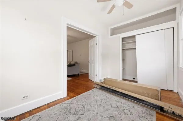 a view of a room with wooden floor and a ceiling fan