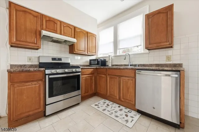 a kitchen with stainless steel appliances granite countertop a sink stove and cabinets