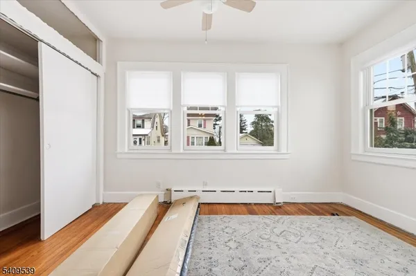 a view of an empty room with a window and wooden floor