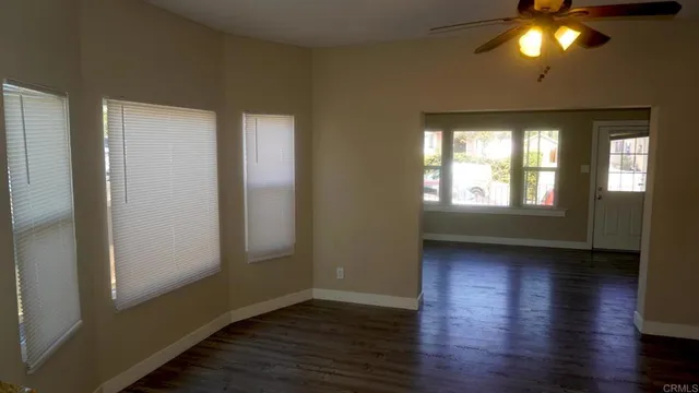 an empty room with wooden floor and windows