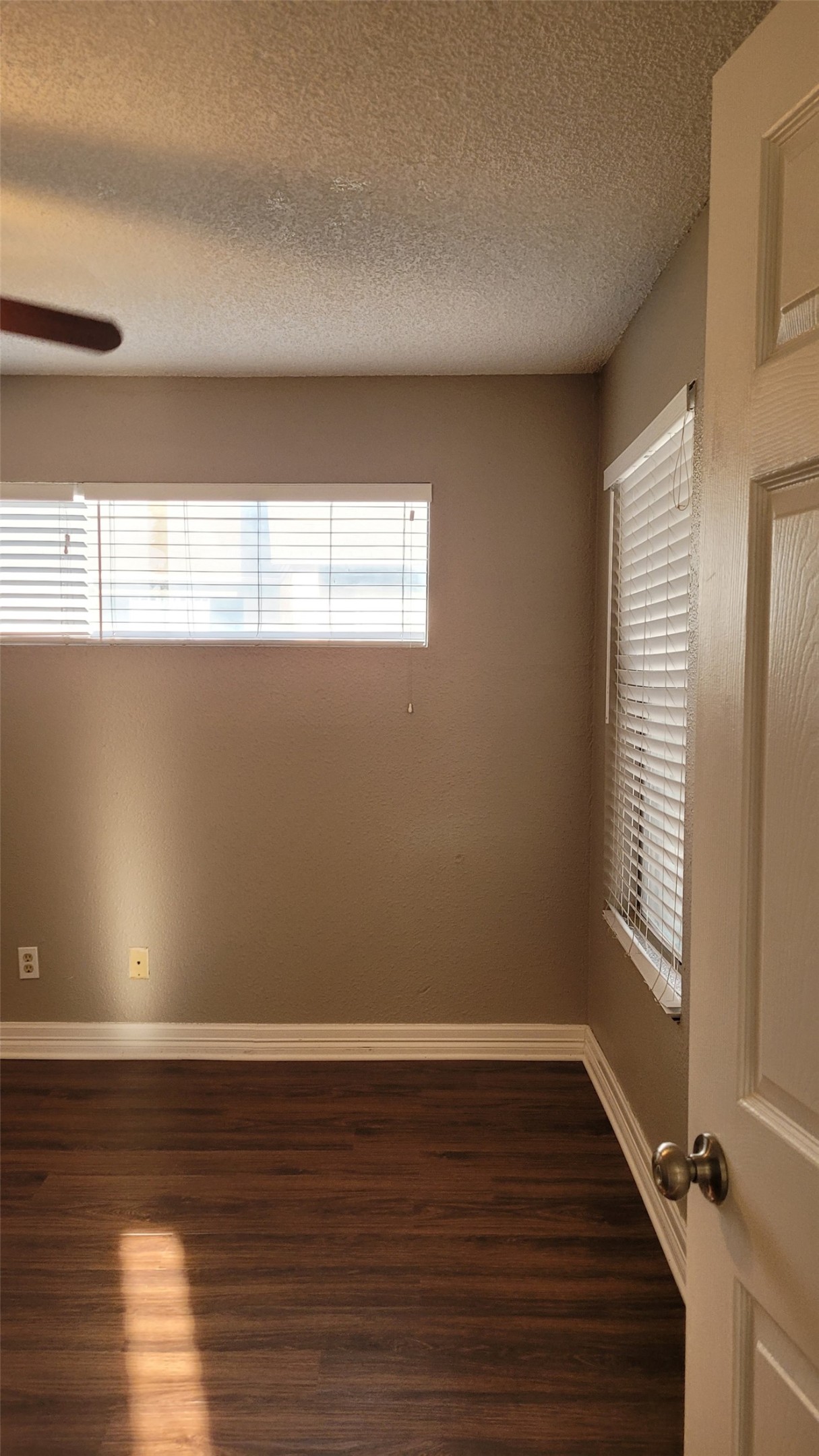 8804 Schick Road, Unit C Austin, TX 78729 - Photo 11 of 26 Spare room featuring dark wood-style flooring, a textured ceiling, and a ceiling fan