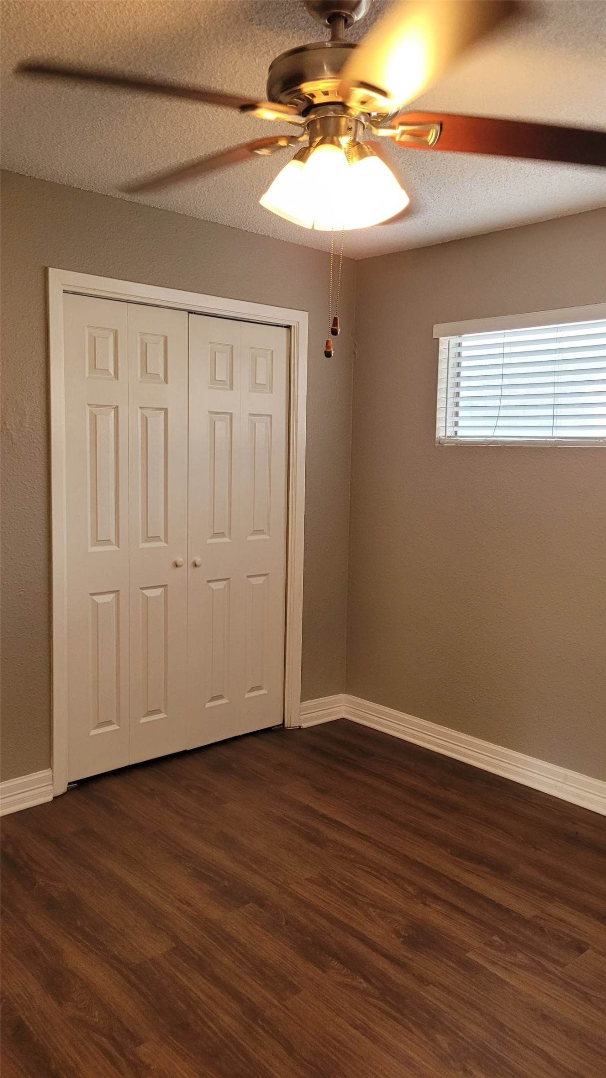 8804 Schick Road, Unit C Austin, TX 78729 - Photo 12 of 26 Unfurnished bedroom featuring a textured ceiling, dark wood-type flooring, ceiling fan, and a closet
