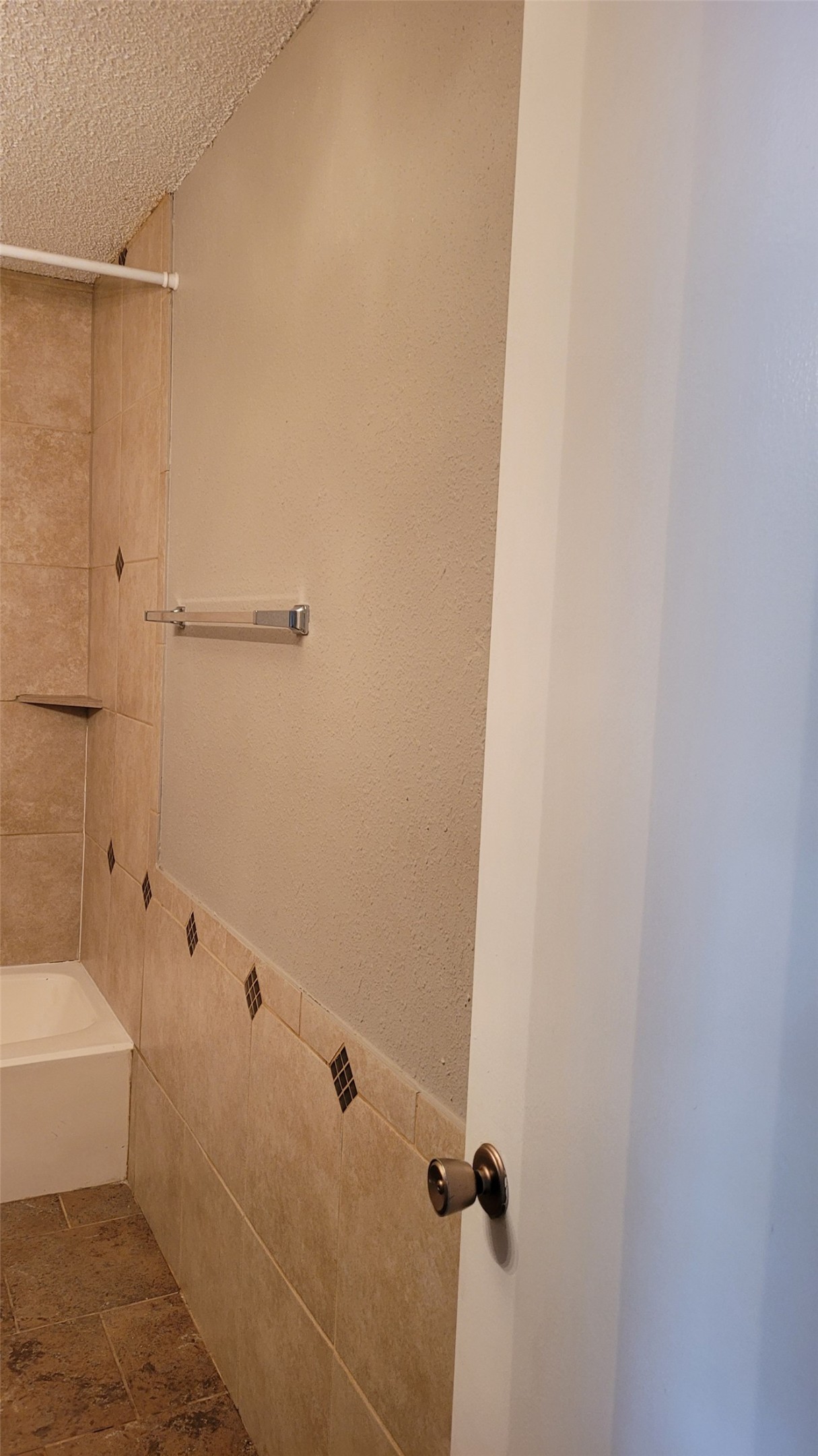 8804 Schick Road, Unit C Austin, TX 78729 - Photo 16 of 26 Bathroom featuring tile walls, washtub / shower combination, a textured ceiling, and stone finish floors