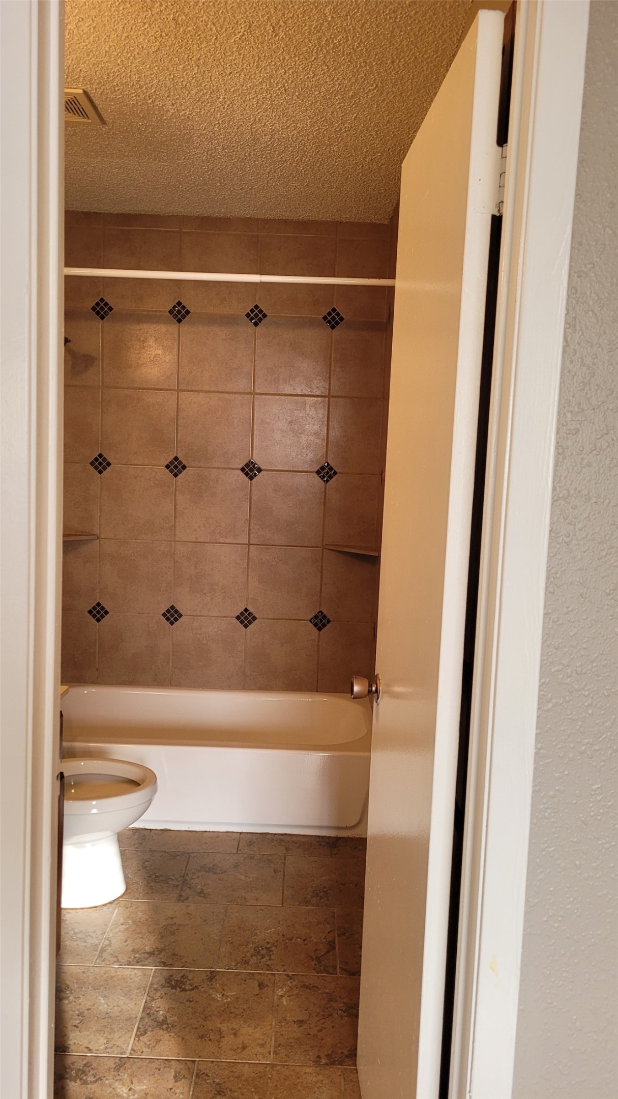 8804 Schick Road, Unit C Austin, TX 78729 - Photo 24 of 26 Full bath with shower / bath combination, a textured ceiling, and stone finish floors