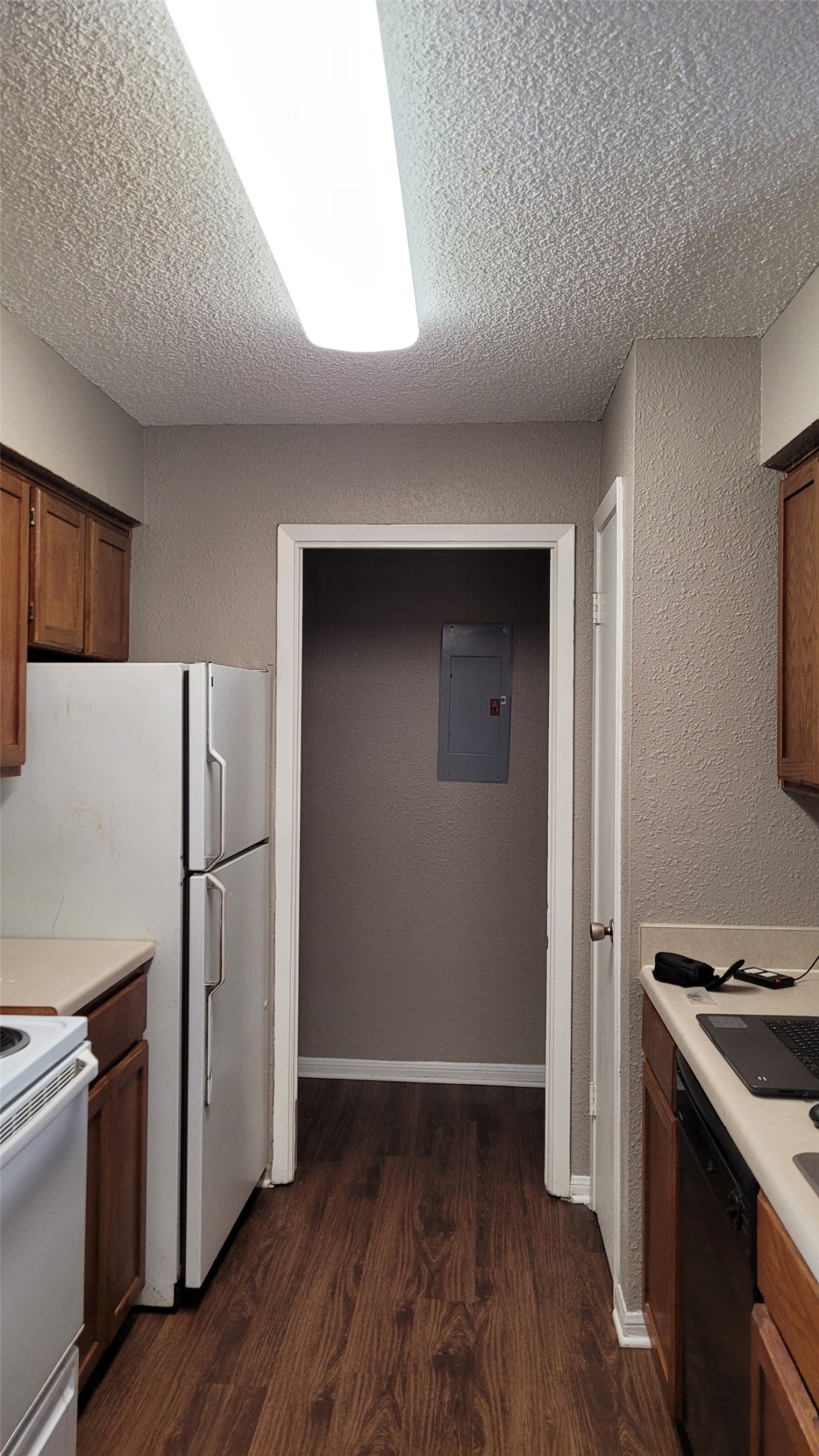 8804 Schick Road, Unit C Austin, TX 78729 - Photo 4 of 26 Kitchen featuring a textured ceiling, light countertops, white appliances, wood finish cabinets, and dark wood-style flooring