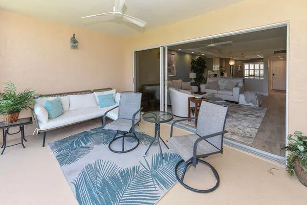a living room with white couches and a dining table with wooden floor