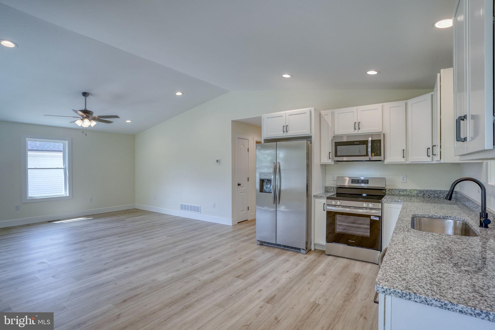 207 Charles Way Georgetown, DE 19947 - Photo 5 of 31 a kitchen with stainless steel appliances granite countertop a refrigerator a sink dishwasher a stove oven and a granite countertops with wooden floor