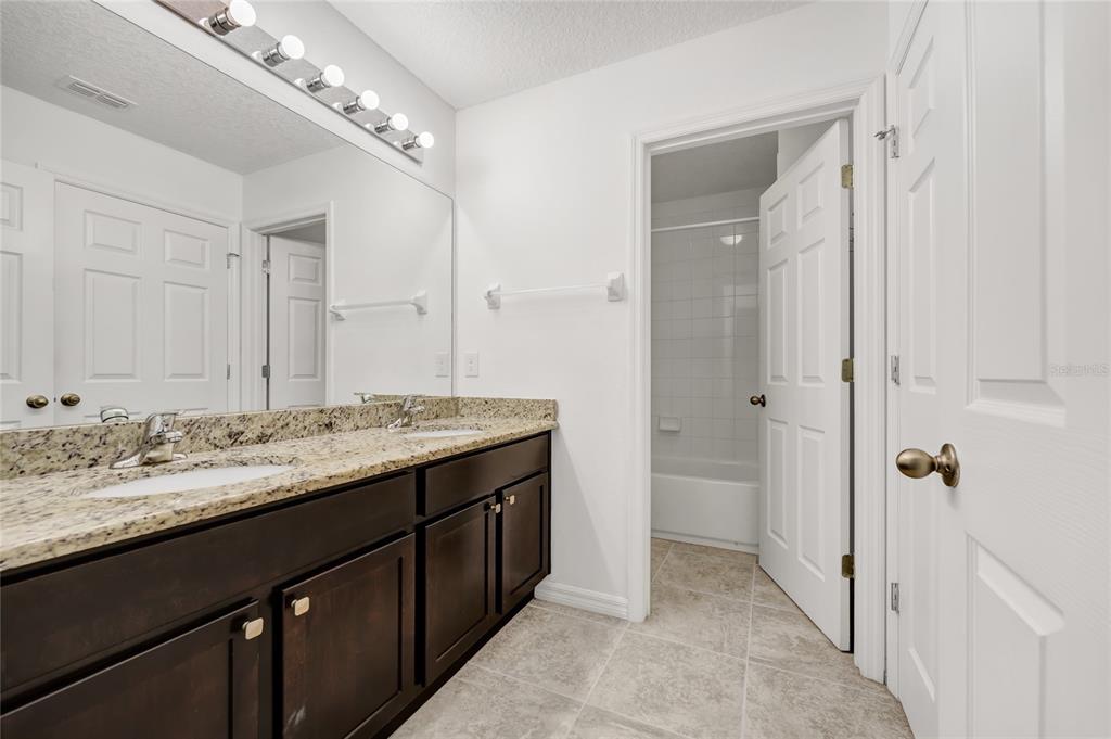 4824 Poolside Drive St. Cloud, FL 34769 - Photo 21 of 29 a bathroom with a granite countertop sink a mirror and a shower