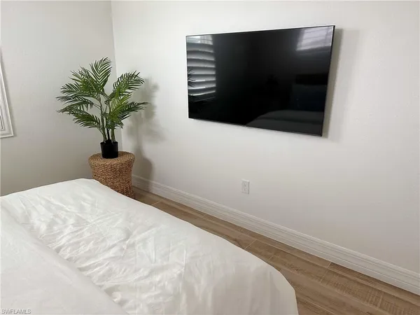 a white bed with a black white bedspread and a wooden floor