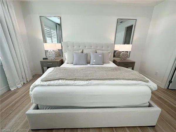 a bed with a white comforter and pillows