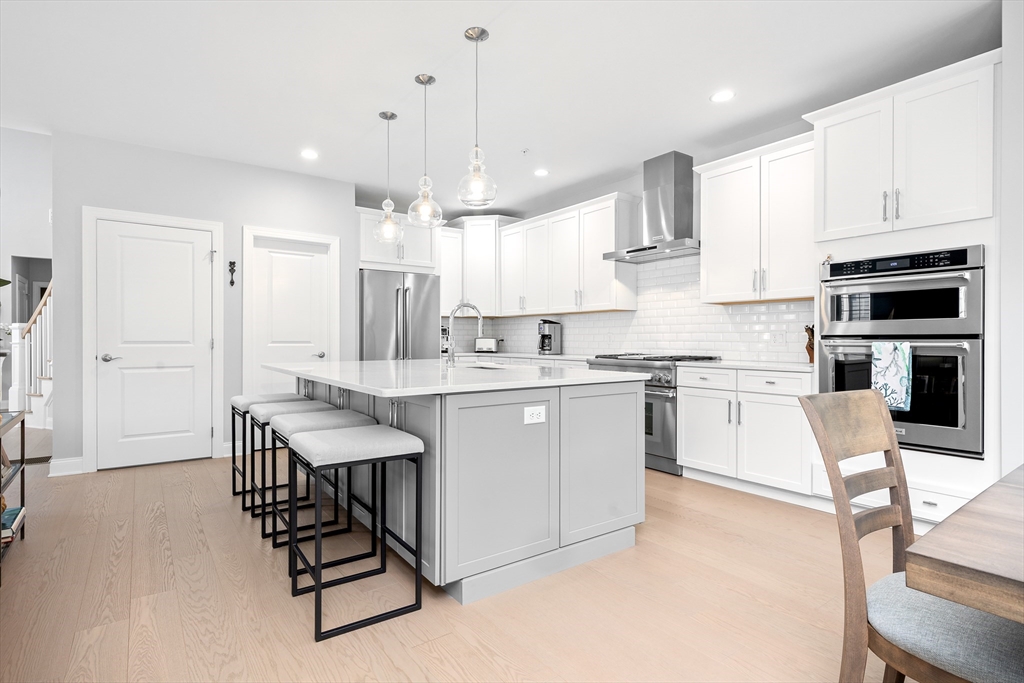 10 Benjamin Lane, Unit 10 Scituate, MA 02066 - Photo 11 of 42 a kitchen with stainless steel appliances kitchen island granite countertop a stove a sink a refrigerator and white cabinets with wooden floor