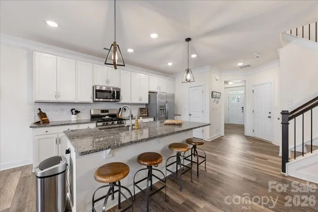 a kitchen with granite countertop a table chairs microwave and cabinets