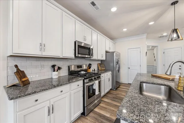 a kitchen with granite countertop a sink stainless steel appliances and white cabinets