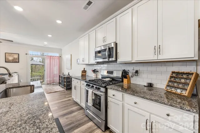 a kitchen with stainless steel appliances granite countertop a stove a sink and a white cabinets