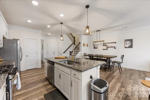 a kitchen that has a table chairs a sink stainless steel appliances and wooden floor