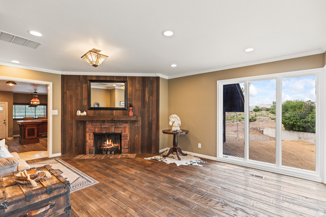 460 Omni Point Road Central Valley, UT 84754 - Photo 20 of 101 Living area featuring rich wood-finish flooring, a brick fireplace with wood paneling, and a large sliding glass door