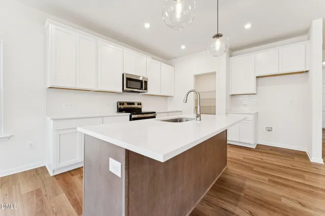a kitchen with kitchen island a sink stainless steel appliances and white cabinets