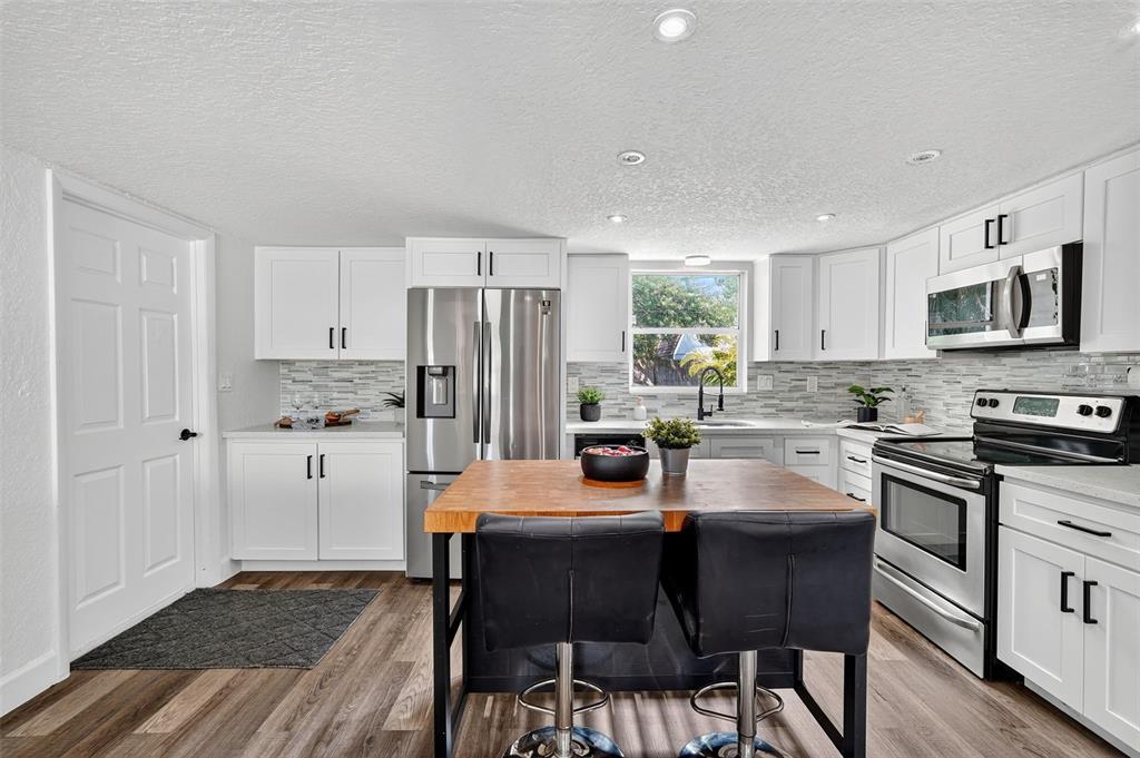 11119 Temple Avenue Seminole, FL 33772 - Photo 11 of 35 a kitchen with stainless steel appliances granite countertop a stove a sink a refrigerator a microwave and cabinets