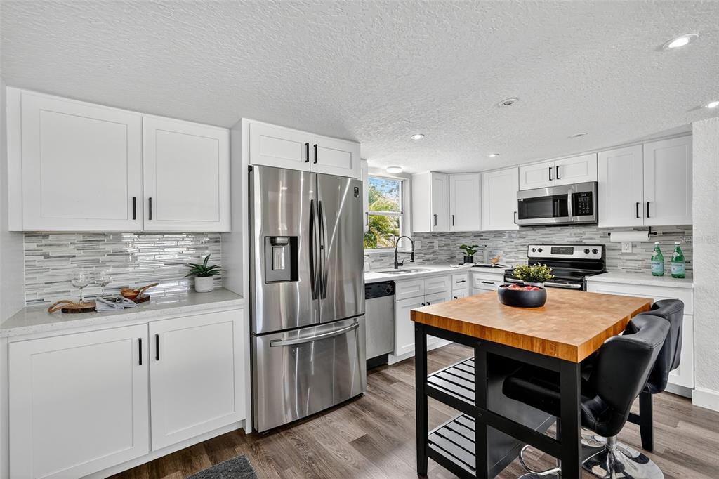 11119 Temple Avenue Seminole, FL 33772 - Photo 7 of 35 a kitchen with stainless steel appliances a refrigerator a stove a sink a dining table and chairs