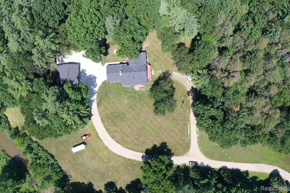 3656 Stanley Road Columbiaville, MI 48421 - Photo 50 of 65 Aerial property view featuring a main residence, an accessory building, expansive green spaces, mature tree coverage, and a natural water feature