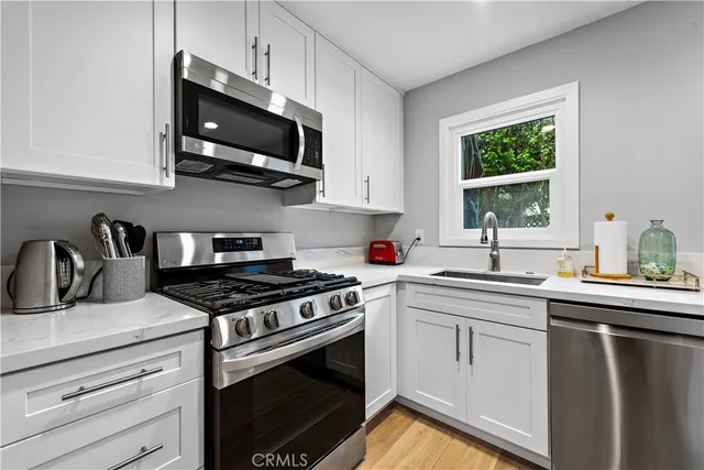 a kitchen with stainless steel appliances granite countertop a sink dishwasher a stove and a microwave oven with cabinets