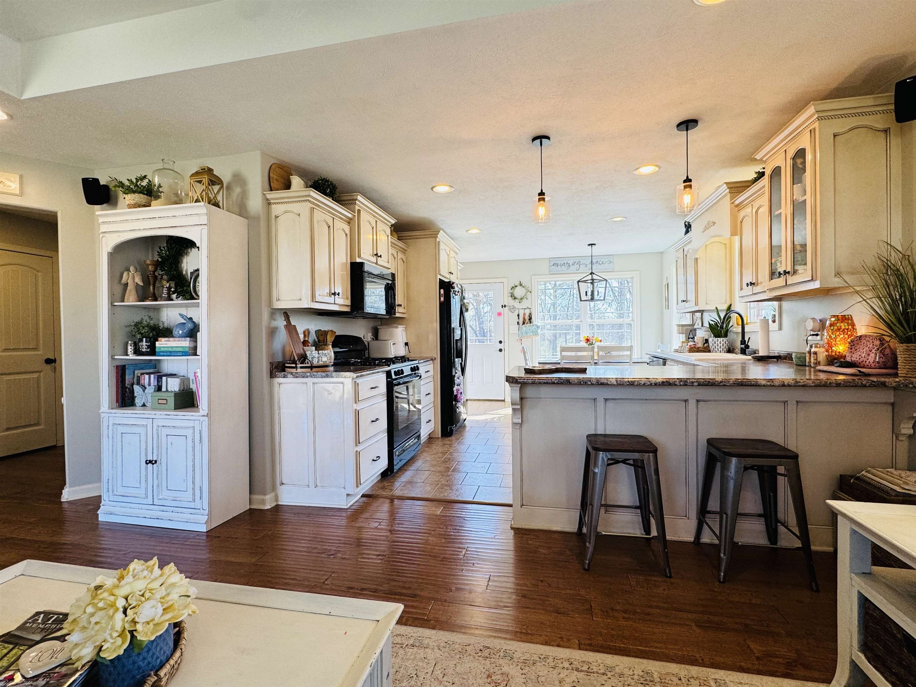 40 Foxtrot Road Adamsville, TN 38310 - Photo 17 of 39 Kitchen featuring a kitchen breakfast bar, dark wood-style flooring, a peninsula, black appliances, and glass insert cabinets