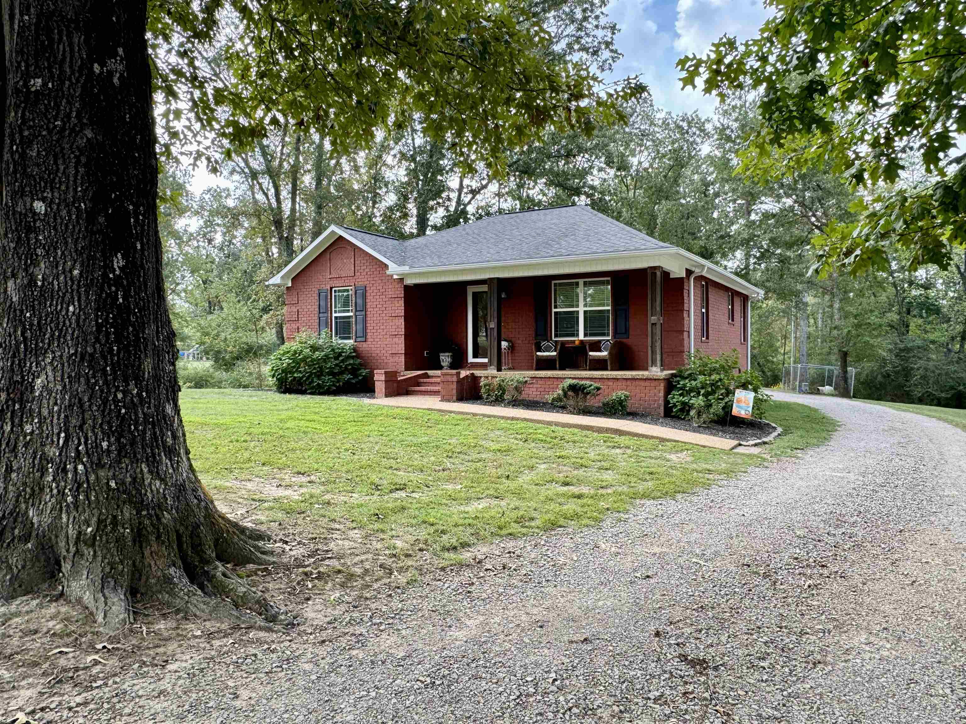 40 Foxtrot Road Adamsville, TN 38310 - Photo 5 of 39 View of front of home featuring roof with shingles, driveway, a front lawn, brick siding, and a porch