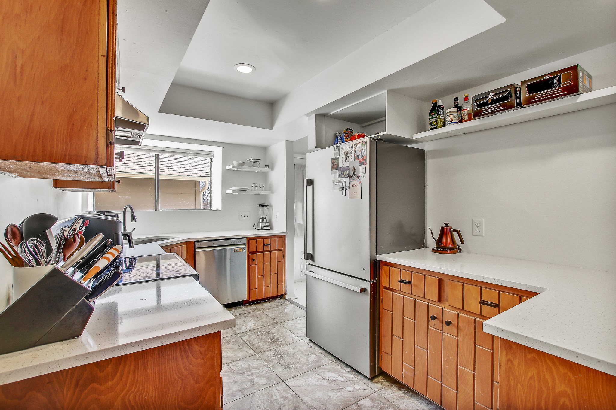 8925 North Plaza, Unit 69 Austin, TX 78753 - Photo 8 of 29 Kitchen with open shelves, light stone countertops, brown cabinetry, stainless steel appliances, and extractor fan