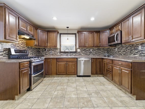 65 Gore Road Revere, MA 02151 - Photo 12 of 35 a kitchen with stainless steel appliances granite countertop a stove sink cabinets and window
