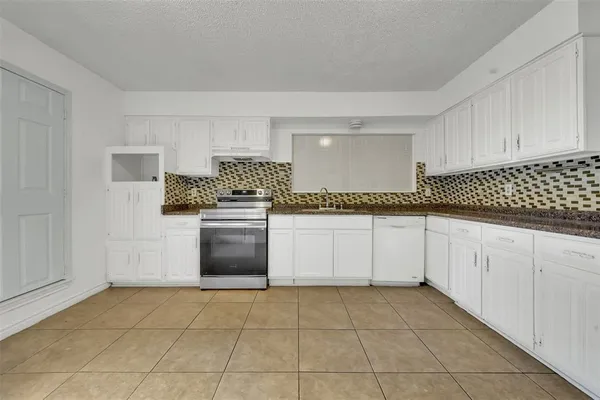 a kitchen with granite countertop white cabinets and appliances
