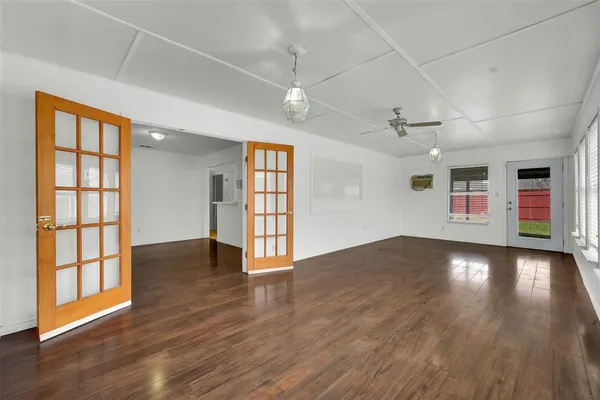 a view of an empty room with wooden floor and a window