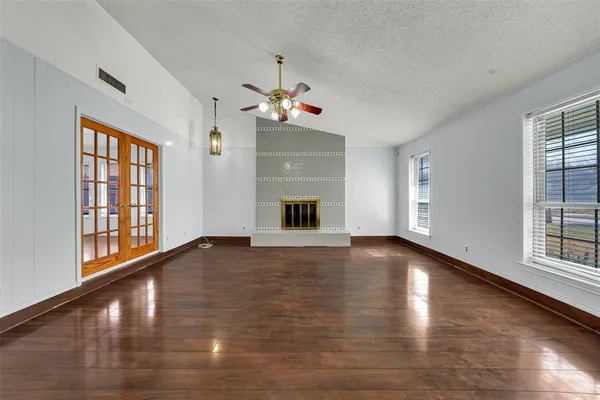 a view of an empty room with a window and wooden floor