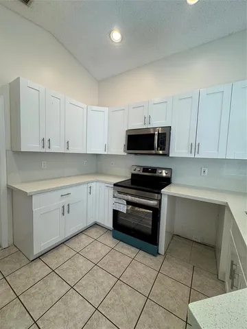 a kitchen with white cabinets and appliances