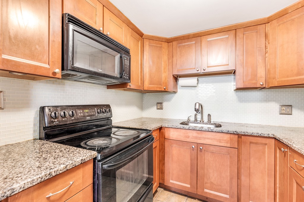 12 Locust Street, Unit 3D Everett, MA 02149 - Photo 11 of 24 a kitchen with granite countertop a stove sink and cabinets