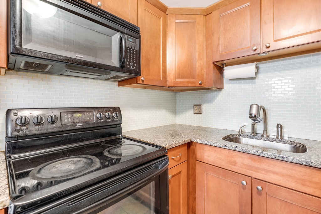 12 Locust Street, Unit 3D Everett, MA 02149 - Photo 13 of 24 a kitchen with stainless steel appliances granite countertop a sink and a stove