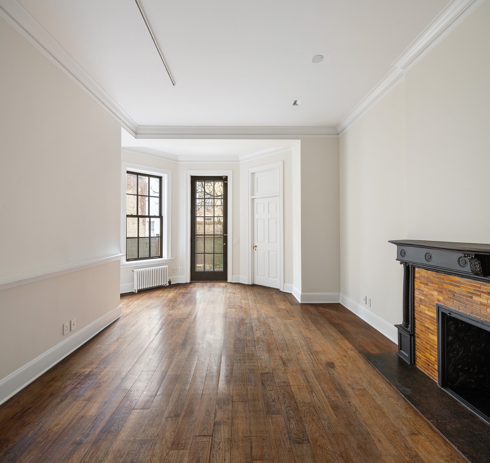 127 East 69th Street, Unit RES 3 Manhattan, NY 10021 - Photo 5 of 10 an empty room with wooden floor fireplace and windows