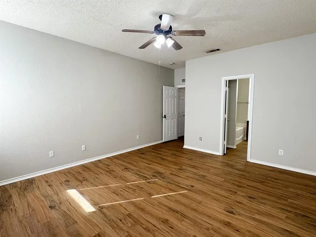 a view of an empty room and chandelier fan