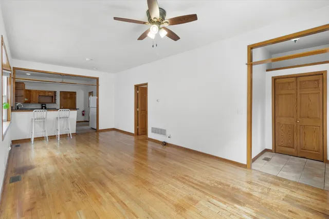 a view of a livingroom with a fireplace a ceiling fan and wooden floor